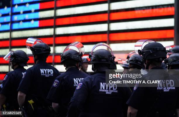 Police officers watch demonstrators in Times Square on June 1 during a "Black Lives Matter" protest. - New York's mayor Bill de Blasio today declared...