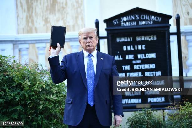 President Donald Trump holds up a bible in front of St John's Episcopal church after walking across Lafayette Park from the White House in...