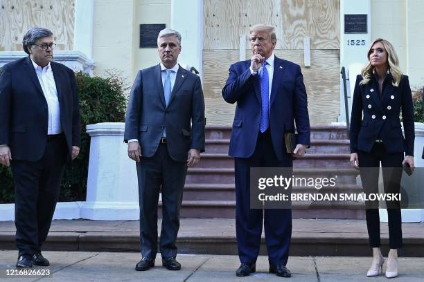 President Donald Trump holds up a Bible as he gestures, alongside US Attorney General William Barr , White House national security adviser Robert...