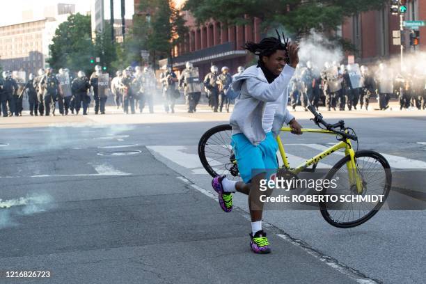 Protestor grabs his bike as the police uses tear gas and rubber bullets to disperse the crowd gathered near the White House on June 1, 2020 as...