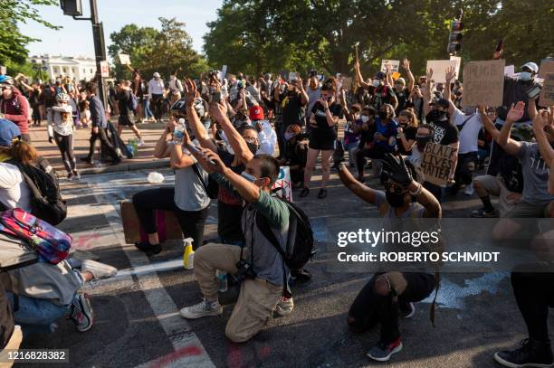 Protestors take a knee and raise their hands as they face riot police near the White House on June 1, 2020 as demonstrations against George Floyd's...