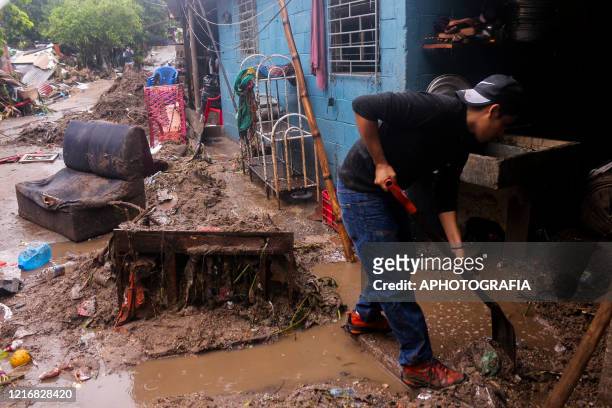 Man shovels mud from his home after being damaged by a mud slide on June 01, 2020 in San Salvador, El Salvador. Government authorities of El Salvador...