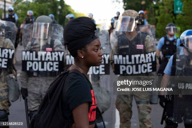 Demonstrator walks in front of a row of military police members wearing riot gear as they push back demonstrators outside of the White House, June 1,...