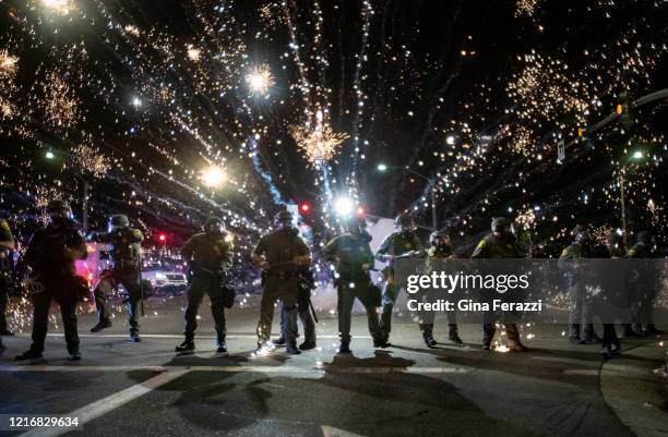 Orange County Sheriff deputies maintain a police block as a firecracker thrown by a protester explodes behind them during a protest against the...