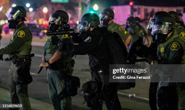 Santa Ana Police officer fires tear gas into the crowd during a protest against the Minneapolis police killing of George Floyd during the coronavirus...