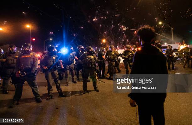 Orange County Sheriff deputies maintain a police block as a firecracker thrown by a protester explodes behind them during a protest against the...