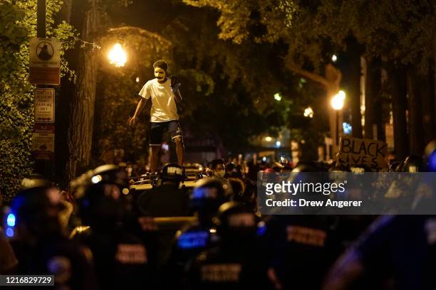 Protester stands atop a vehicle as he is surrounded by law enforcement during a protest on June 1, 2020 in downtown Washington, DC. Protests and...