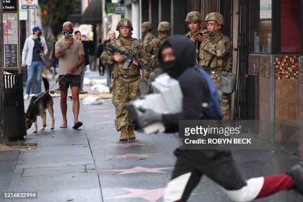 Suspected looter carrying boxes of shoes run past National Guard soldiers in Hollywood, California, June 1 after a demonstration over the death of...