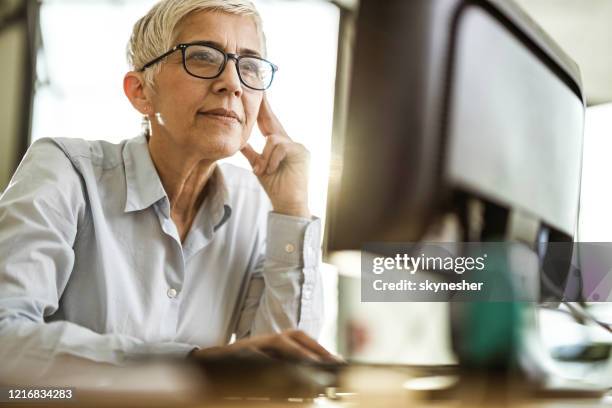 concentrated senior businesswoman working on pc in the office. - mature woman screen stock pictures, royalty-free photos & images