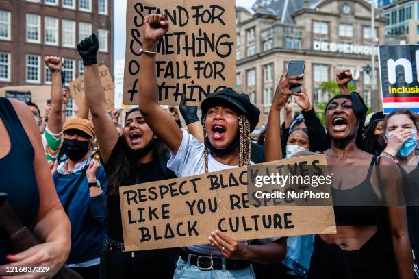Black woman is screaming while holding a big placard, during the massive solidarity protest against anti-black violence in the US and EU, that took...