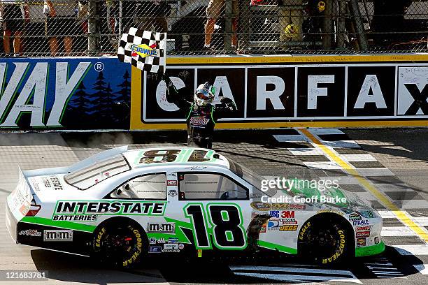 Kyle Busch, driver of the Interstate Batteries Toyota, celebrates with the checkered flag after winning the NASCAR Sprint Cup Series Pure Michigan...