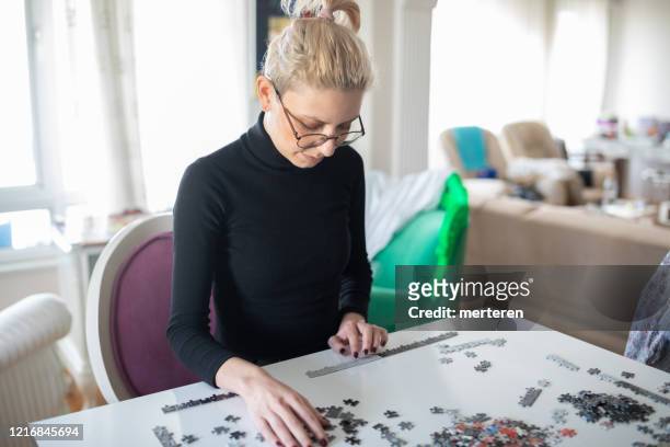 young famale playing puzzle in quarantine - deterioration stock pictures, royalty-free photos & images