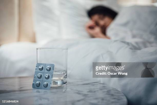 close up shot of pills and a glass of water - slaappil stockfoto's en -beelden