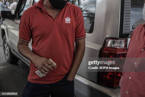 Man working at a gasoline station receives dollars as payment. Nicolas Maduro's government received a shipment of fuel from Iran as national...