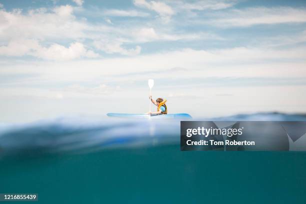 boy paddling canoe through the sea - rowing competition stock pictures, royalty-free photos & images