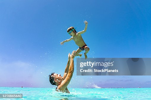 Father is tossing up a son in the air Father is tossing up a son in the air