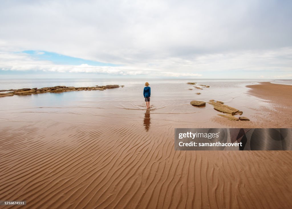 Boy walking along beach, Bedford, Halifax, Nova Scotia, Canada