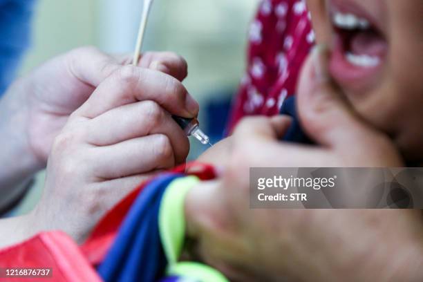 This photo taken on June 1, 2020 shows a child receiving a pneumococcal conjugate vaccine at a community healthcare centre in Zhengzhou in China's...