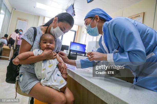 This photo taken on June 1, 2020 shows a child receiving a pneumococcal conjugate vaccine at a community healthcare centre in Zhengzhou in China's...