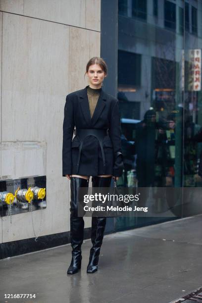 Model Giedre Dukauskaite attends the Dion Lee show in a black blazer dress with a harness belt, thigh-high black leather boots, and a triangular...