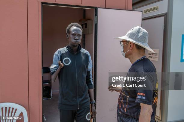 South Sudanese Paralympic 100m and 200m runner Michael Machiek Ting Kutjang passes Japanese volunteer translator Fumio Matsumura as he prepares to...