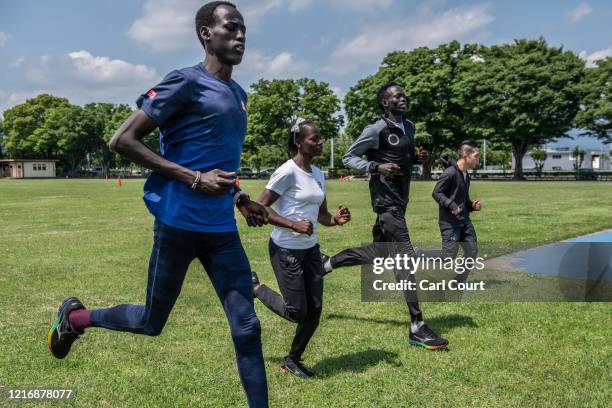 South Sudanese Olympians Abraham Majok Matet Guem, Moris Lucia, and Joseph Akoon Akoon and Japanese Paralympian sprinter Masatoshi Sorimachi warm up...