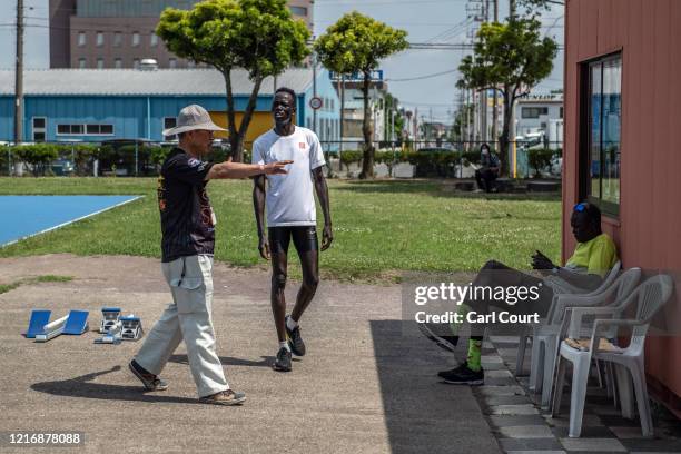 South Sudanese Olympic hurdler Joseph Akoon Akoon listens to a translator while coach Joseph Rensio Tobia Omirok checks his phone as he trains at an...