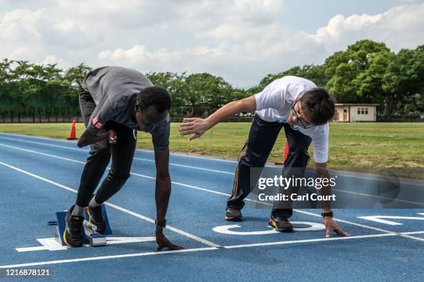 Japanese coach Masanori Yamagishi instructs South Sudanese Paralympic 100m and 200m runner Michael Machiek Ting Kutjang during a training session at...