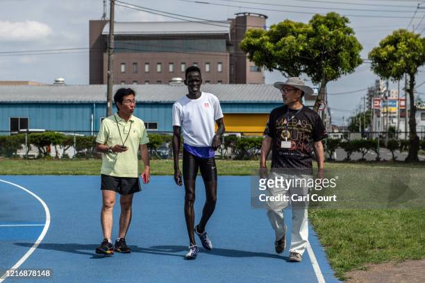 South Sudanese Olympic hurdler Joseph Akoon Akoon listens to a translator as coach Yasuhiro Ito gives instruction during a training session at an...