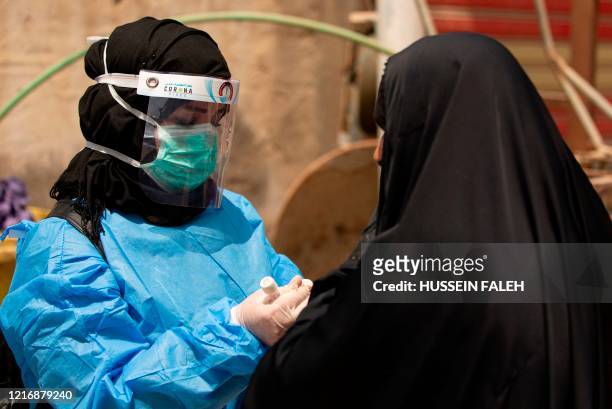 Medical worker prepares to take a swab from a woman being tested for COVID-19 coronavirus disease, in the 5-Miles district of Iraq's southern Basra...