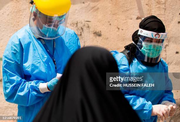 Medical workers dressed in PPE prepare to take swabs from subjects being tested for COVID-19 coronavirus disease, in the 5-Miles district of Iraq's...