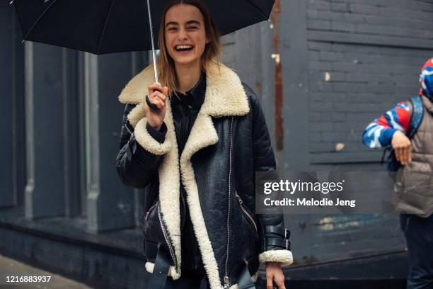 Model Maartje Verhoef carries a black umbrella and wears a black shearling bomber jacket after the Gabriela Hearst show on February 11, 2020 in New...