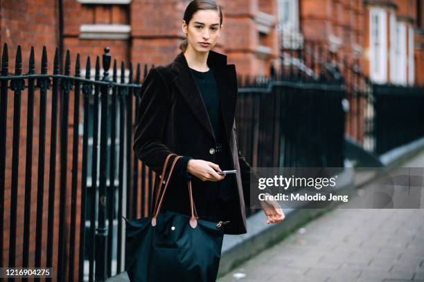 Model Justi Ageitos wears a brown velvet jacket and black Longchamp tote bag after the J.W. Anderson show during London Fashion Week February 2020 on...