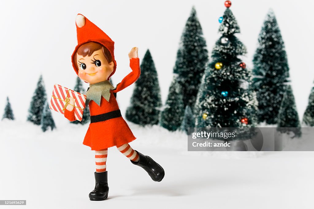 Vintage Christmas doll in front of Christmas trees