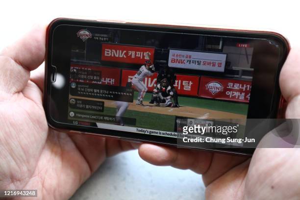 Man watches the LG Twins intra-team game on his mobile phone which is broadcast online for fans from a empty Jamshil baseball stadium as South...