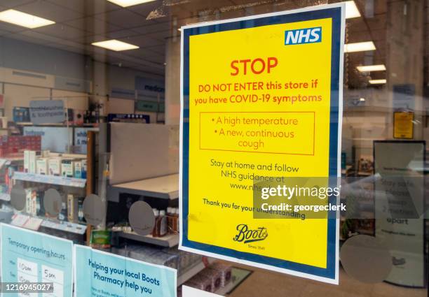 pharmacy sign with guidance for people with covid-19 symptoms - boots pharmacy stock pictures, royalty-free photos & images