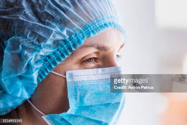 portrait of a doctor woman in a medical mask and a protective cap. - pandemic illness photos et images de collection