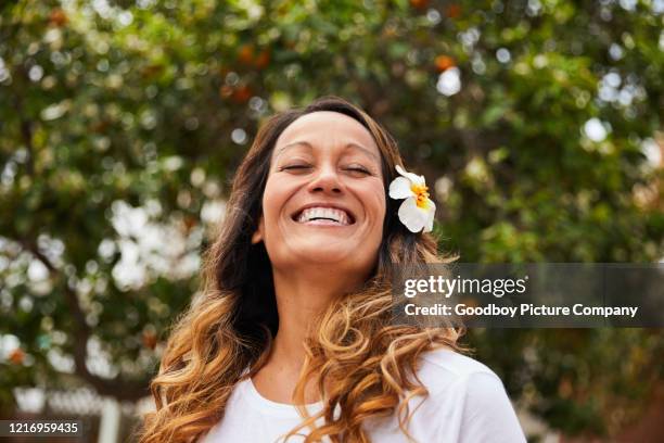 mulher madura do lado de fora com uma flor no cabelo e rindo - beautiful polynesian women - fotografias e filmes do acervo