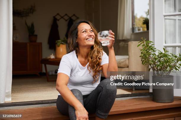 smiling mature woman sitting on her patio drinking water - água potável imagens e fotografias de stock