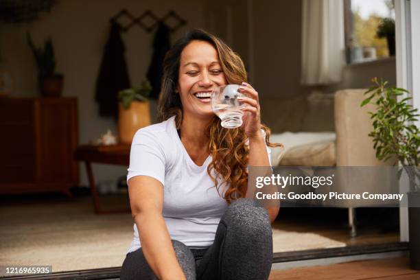 lachende reife frau trinkwasser auf ihrer terrasse - drank stock-fotos und bilder