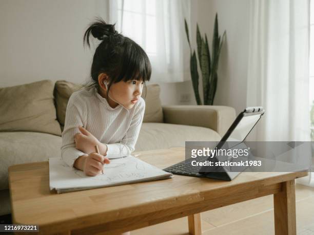 kleines mädchen macht ihre hausaufgaben mit digitalen tablet. - young girls homework stock-fotos und bilder