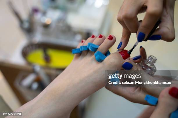 woman in nail salon receiving pedicure by beautician - pedicure stock pictures, royalty-free photos & images