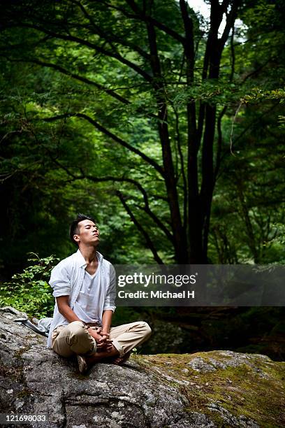 man who meditates on rock - cross legged stock pictures, royalty-free photos & images
