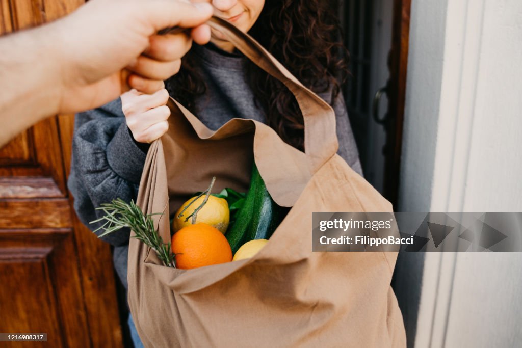 Ein Mann liefert eine Tüte mit Gemüse und Obst