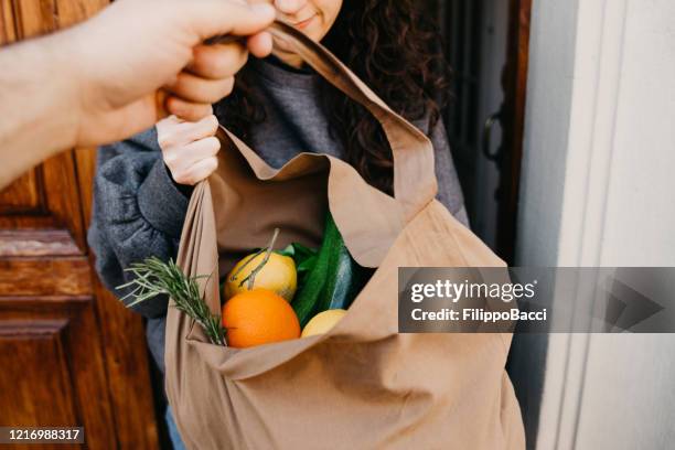 un uomo sta consegnando un sacchetto di verdure e frutta - consegna a domicilio foto e immagini stock