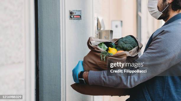 un uomo sta consegnando un sacchetto di verdure e frutta - consegna a domicilio foto e immagini stock