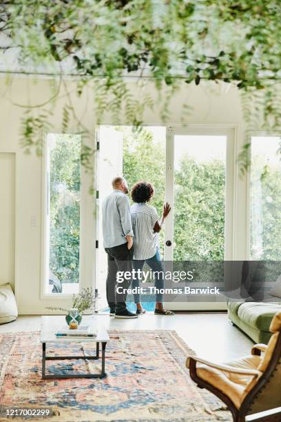 couple looking out doorway of home to backyard - woman look straight black shirt stock pictures, royalty-free photos & images