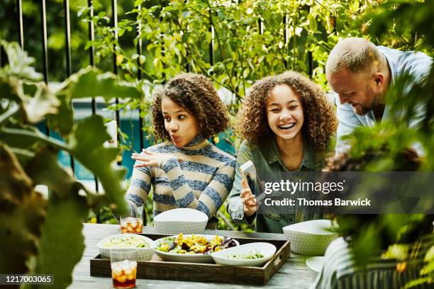 laughing family playing with photos on smart phones during backyard picnic - girl white background stock pictures, royalty-free photos & images