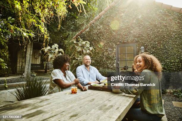 laughing family sharing meal at picnic table in backyard - casual couple photos et images de collection