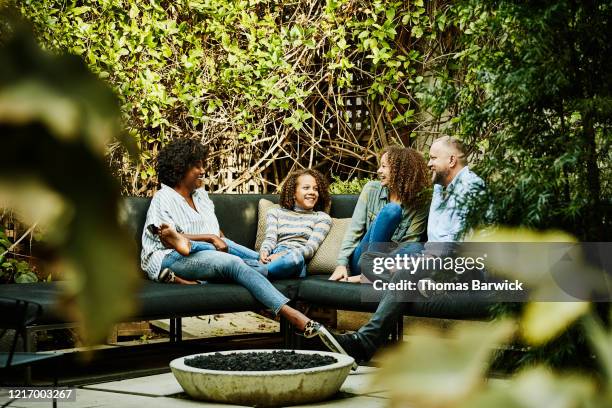 smiling family hanging out by fire pit in backyard - garden talking photos et images de collection